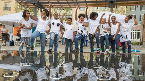 A group of people are standing on a reflective surface.