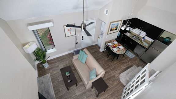 View of Fusion Orlando furnished apartment living space from loft. Open concept living room and kitchen with ceiling fan and in unit laundry. Apartments in Orlando.