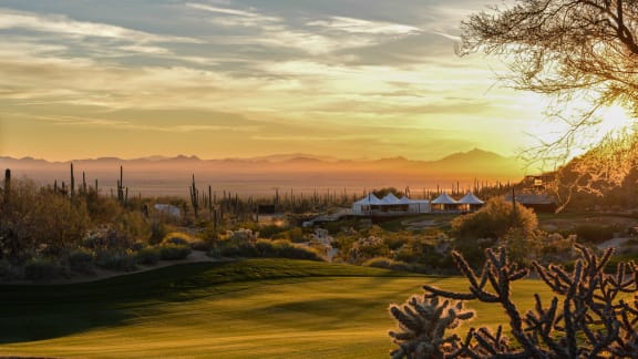 the golf course at sunset with the mountains in the background