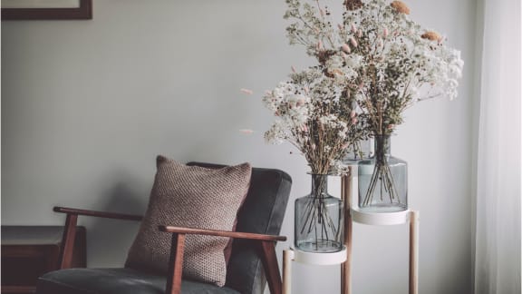 A living room with a chair and a vase of flowers on a table, enhancing the space with natural beauty.