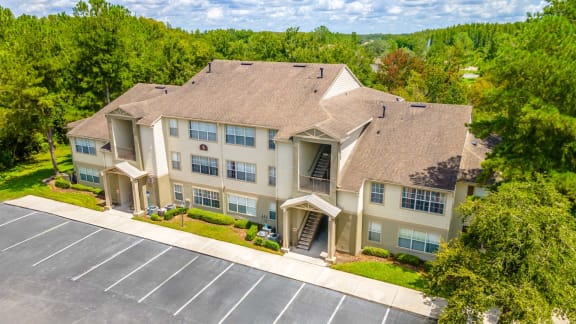 a large apartment building with a parking lot and trees