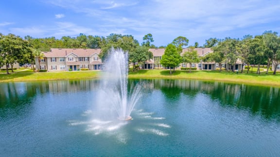 a fountain in the middle of a lake with apartments in the background