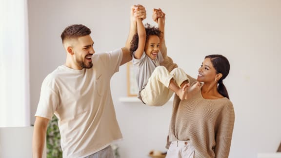 a man and woman holding their child up in the air with their hands in the