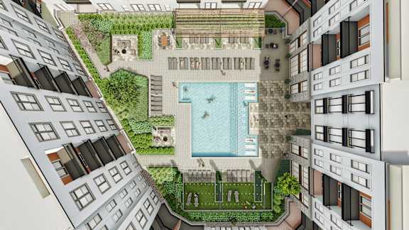 A pool surrounded by lounge chairs and umbrellas in a courtyard.