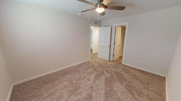 Primary Bedroom with a ceiling fan ,carpeted floor, and walk-in closet.