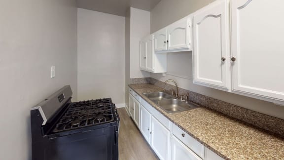 a kitchen with white cabinets and granite counter tops and a black stove