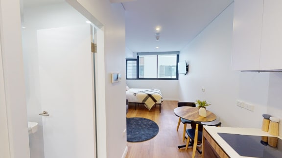 a living room with a table and a bedroom in the background