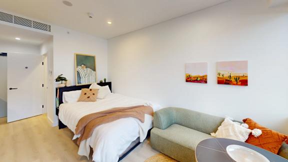 A bedroom with a bed, a couch, and a painting on the wall.