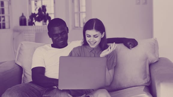 a man and woman sitting on a couch with a laptop