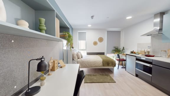 a bedroom with a bed and a kitchen in a room