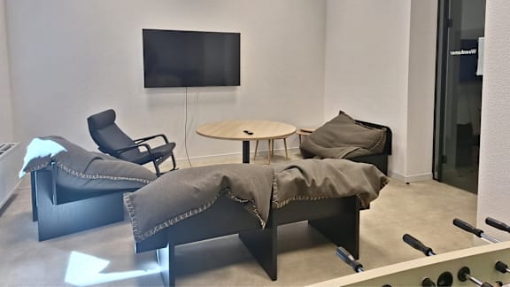 A modern lounge area with a television, chairs, and a table.