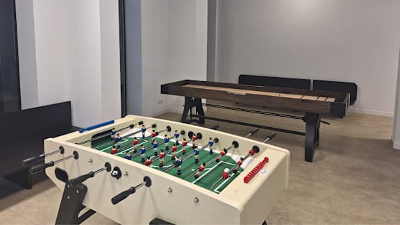 A foosball table is in a room with a bench.