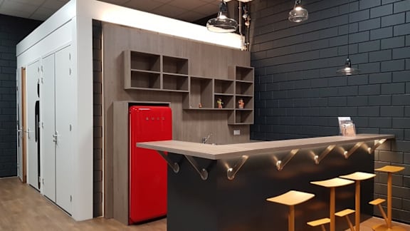 A modern kitchen with a red fridge and wooden cabinets.
