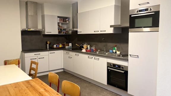 A modern kitchen with white cabinets and a wooden table.