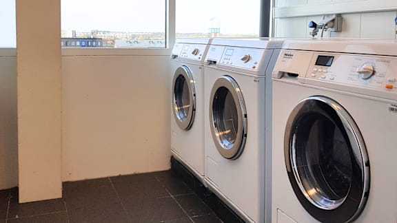 A row of white front load washing machines in a laundromat.