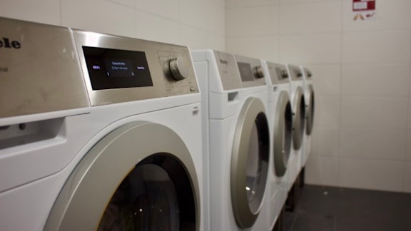 A row of white front load washing machines in a laundromat.