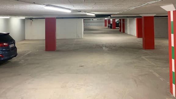 A car is parked in a parking garage with red and white columns.