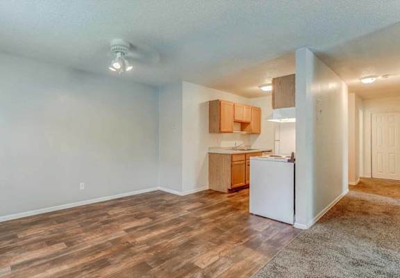 A kitchen area with a white refrigerator and wooden flooring.