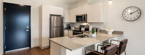 a kitchen with white cabinets and a large island with two chairs