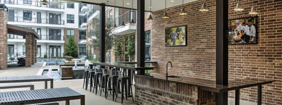 a large open space with a brick wall and a long bar with stools and tables