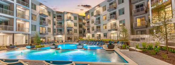 an apartment complex with a swimming pool and lounge chairs