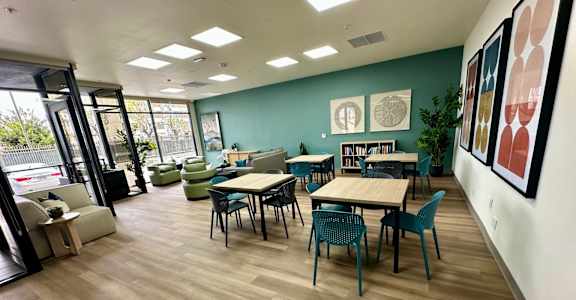 A room with tables and chairs and a bookshelf.