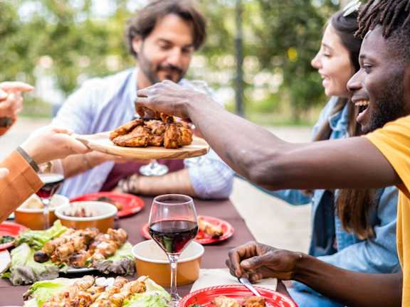 Friends Smiling and Eating Food Together Outside