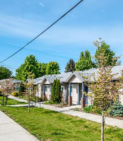 A row of houses with a sidewalk in front.