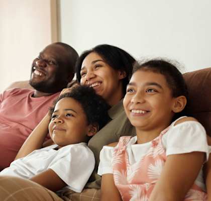 A family sits on a sofa and looks off-camera