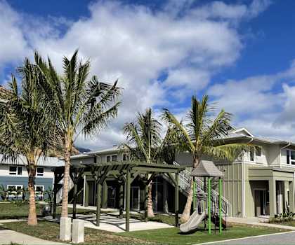A playground area is located in front of a two-story house.