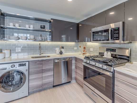 A modern kitchen with a washing machine and a microwave oven.