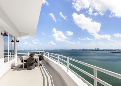 a balcony with a view of the water and a patio with chairs at The Hamilton, Miami, FL