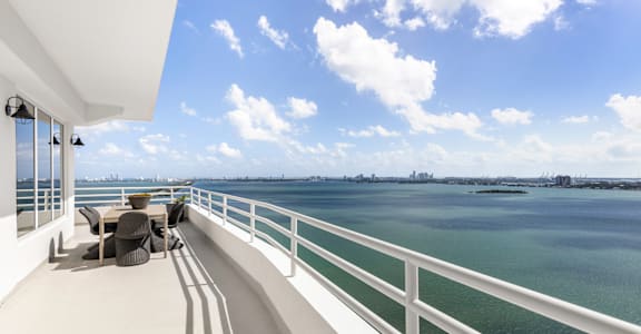 a balcony with a view of the water and a patio with chairs at The Hamilton, Miami, FL