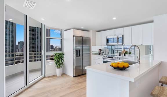 A modern kitchen with a stainless steel refrigerator and grey cabinets.