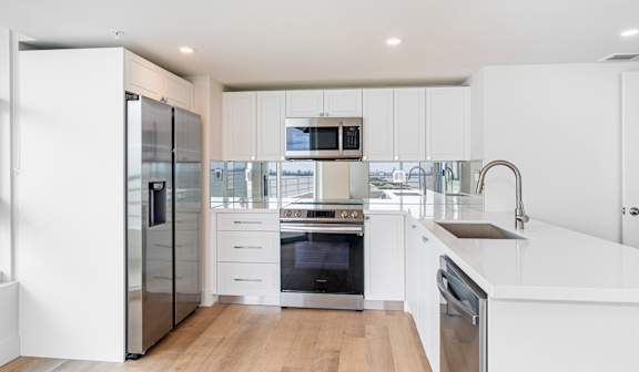 A modern kitchen with white cabinets and stainless steel appliances. at The Hamilton Apartments, Miami, FL 33137