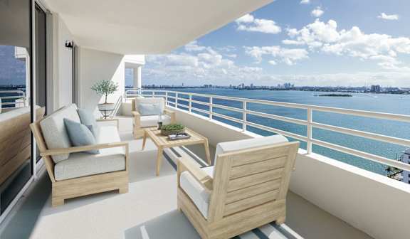 a balcony with two chairs and a table overlooking the ocean at The Hamilton, Miami, 33137