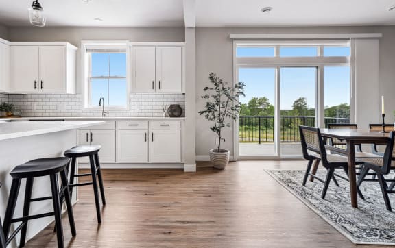 a kitchen and dining room with a large window and a door to a balcony