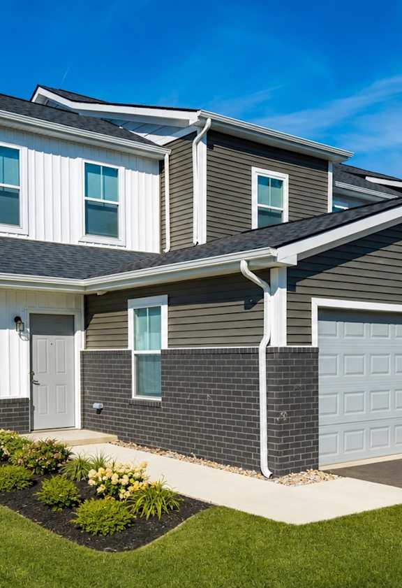 A modern house with a white and grey exterior and a well-maintained lawn.