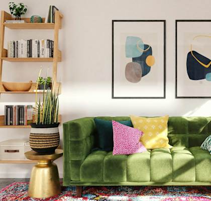 A green couch with pillows and two framed pictures on the wall.