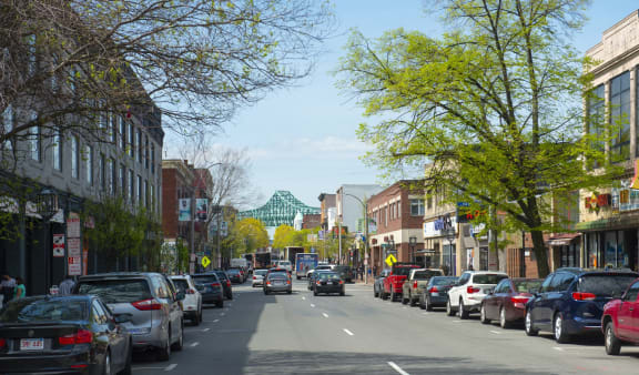 a city street with cars parked on the side of the road and a green bridge