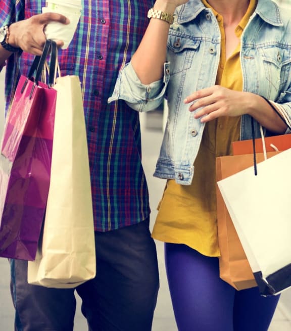 Man and Woman Walking Down Street Holding Shopping Bags