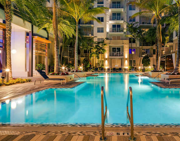 A large swimming pool surrounded by palm trees and lounge chairs.