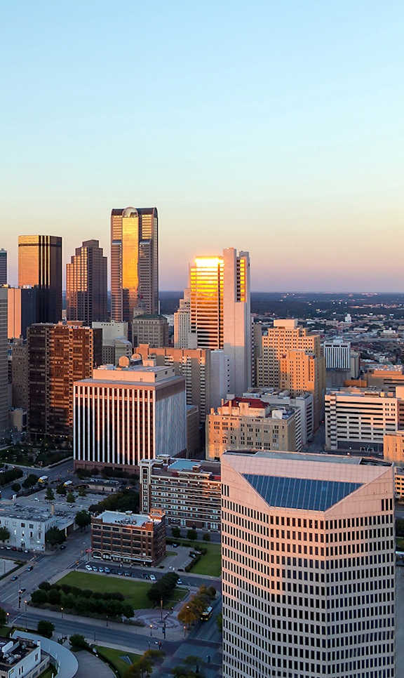 A cityscape with a mix of modern and older buildings under a clear sky.