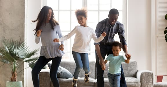 a family of four jumps in a living room