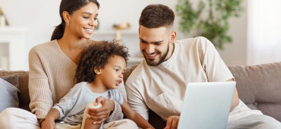 a family sitting on a couch looking at a laptop computer at Glen Hollow, Decatur, GA, 30034
