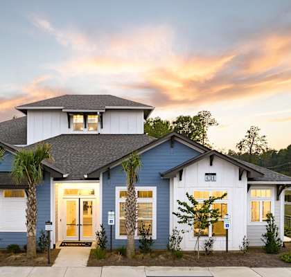 a blue and white house with a sunset behind it