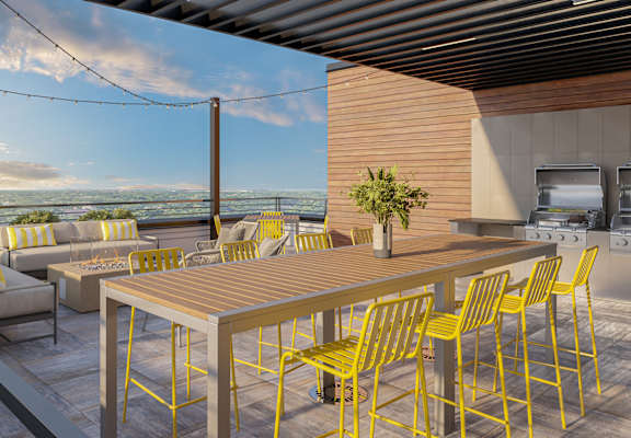 a patio with a wooden table and yellow chairs