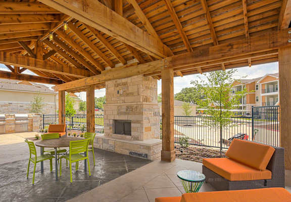 A patio with a fireplace and chairs.