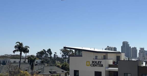 A plane flying over a building with the words "FOLEY CENTER" on it.