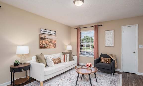 A living room with a white couch, a coffee table, and a framed picture on the wall.
